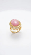 Pink oval cabochon stone gold-plated statement ring with cubic zirconia pavé halo on white background – AureliaBlends