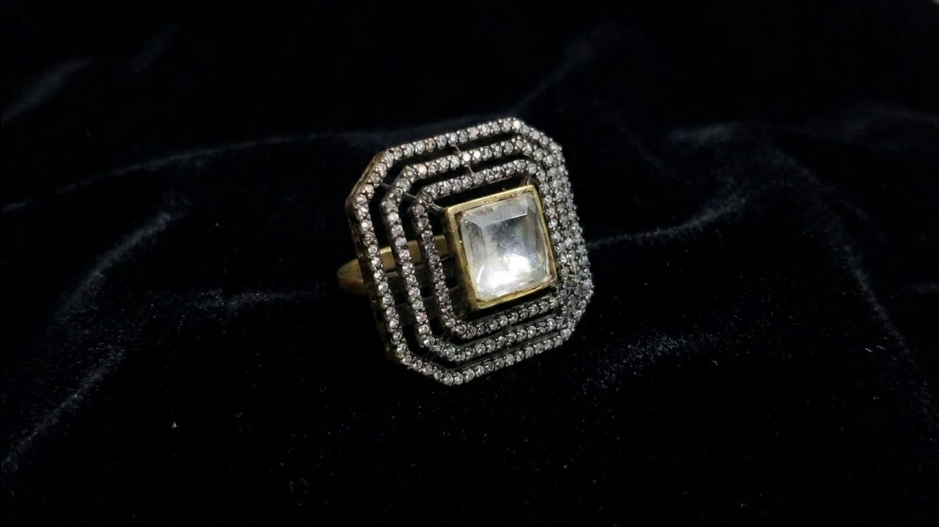 Crystal square CZ statement ring on black velvet showing Art Deco geometric halo setting and gold band – AureliaBlends