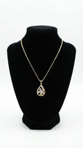 Gold CZ clover teardrop pendant necklace laid flat on cream fabric with ring box and loose crystals – AureliaBlends