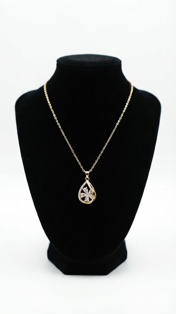 Gold CZ clover teardrop pendant necklace laid flat on cream fabric with ring box and loose crystals – AureliaBlends