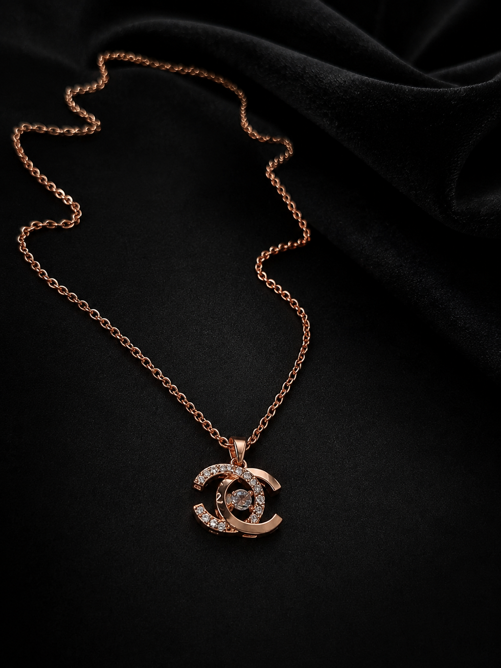 Rose gold CZ double-C pendant necklace draped on black velvet background – AureliaBlends