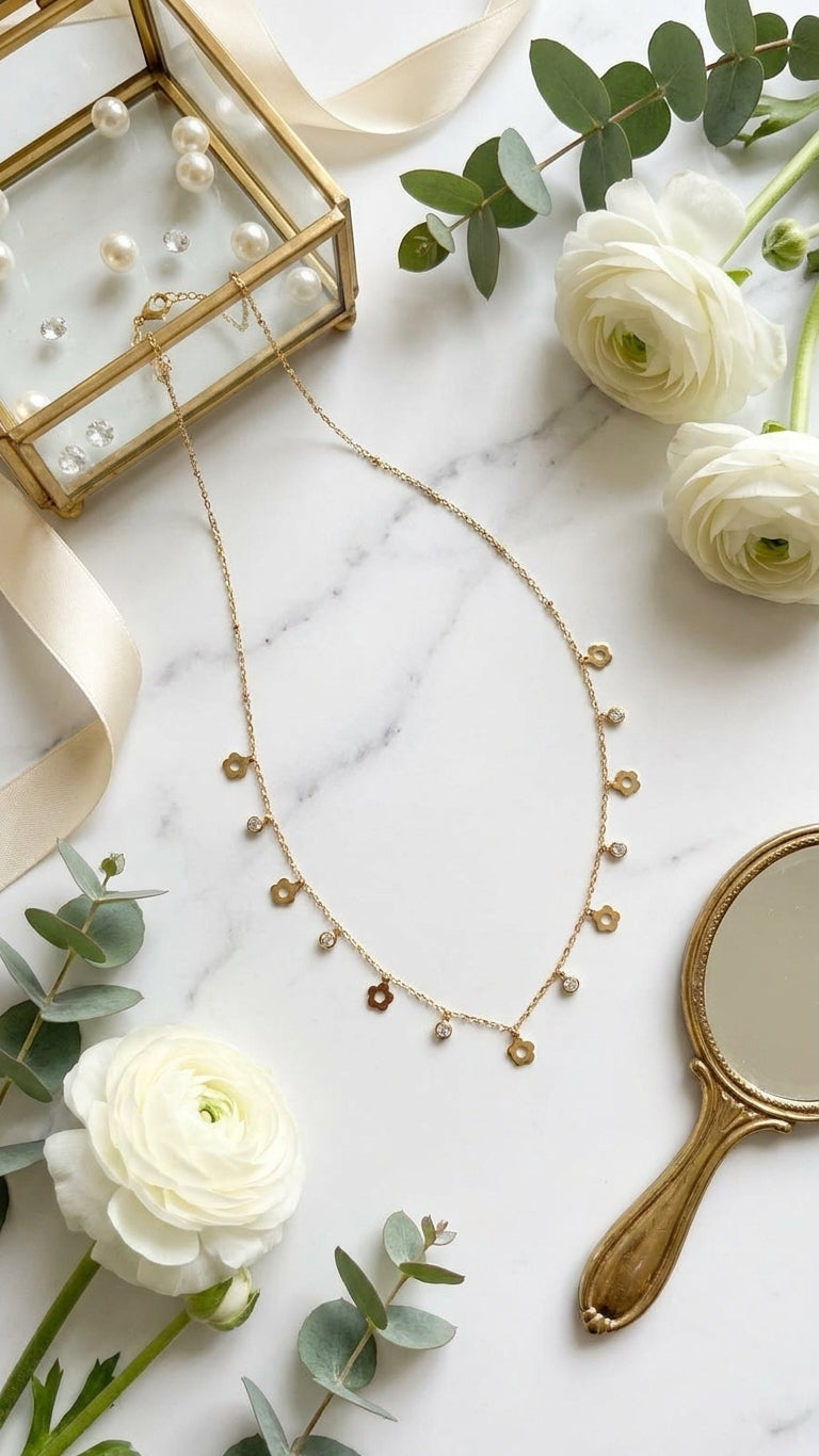 Gold flower charm necklace with CZ drops in black velvet box surrounded by pink roses and baby's breath – wedding jewelry