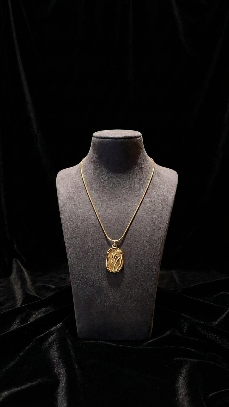 Woman wearing gold tulip engraved oval locket pendant necklace on snake chain with pearl bracelet and gold rings – bridal jewelry look