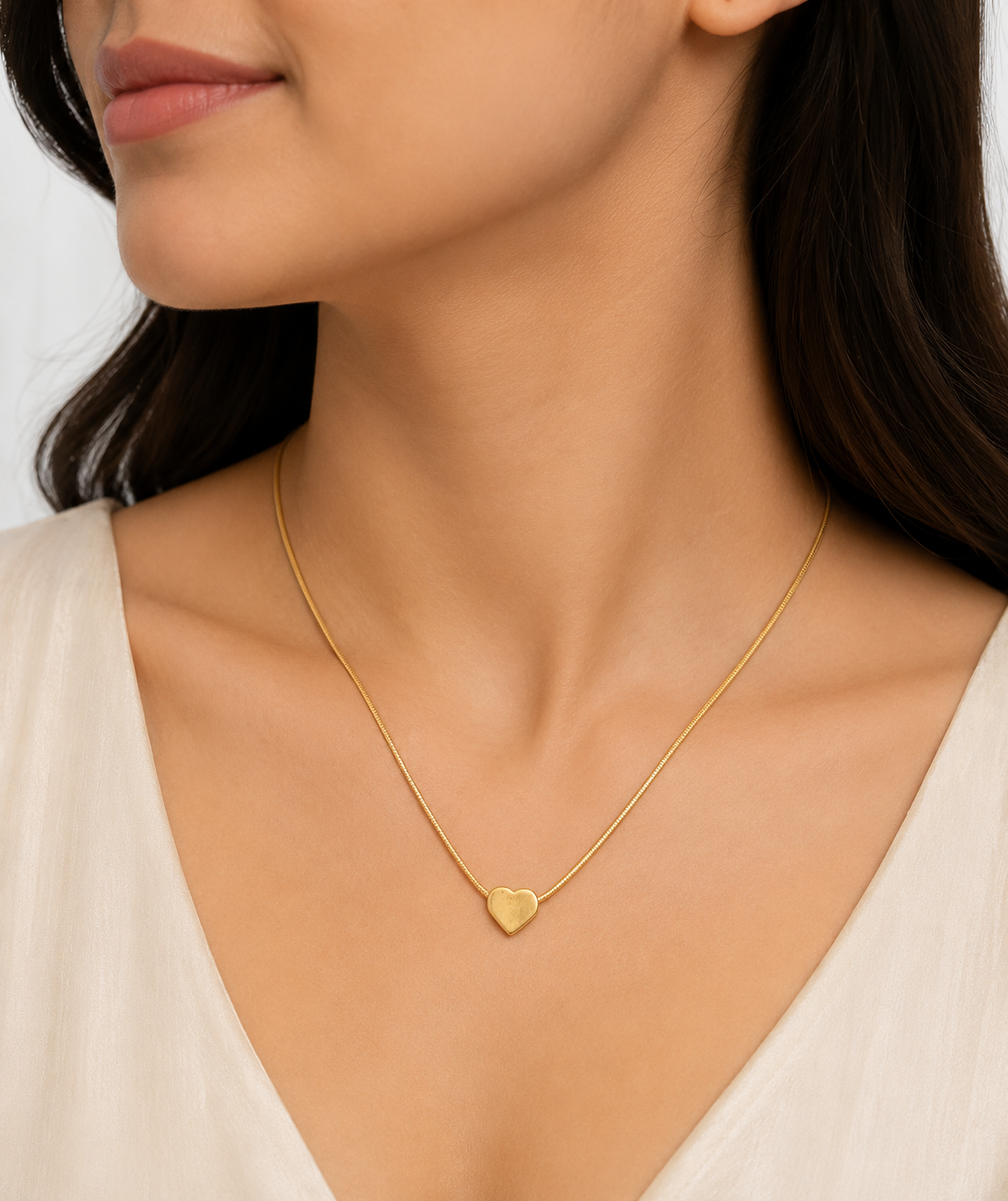 Dainty gold solid heart charm necklace on snake chain flatlay on black satin with dried flowers and black jewelry box – elegant gold heart necklace