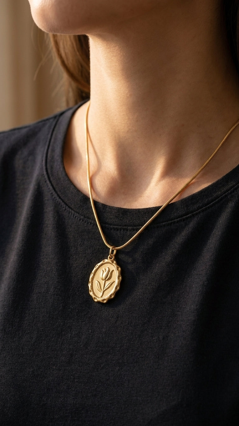 Gold oval tulip engraved medallion necklace on black velvet jewelry bust against dark moody background – statement necklace AureliaBlends