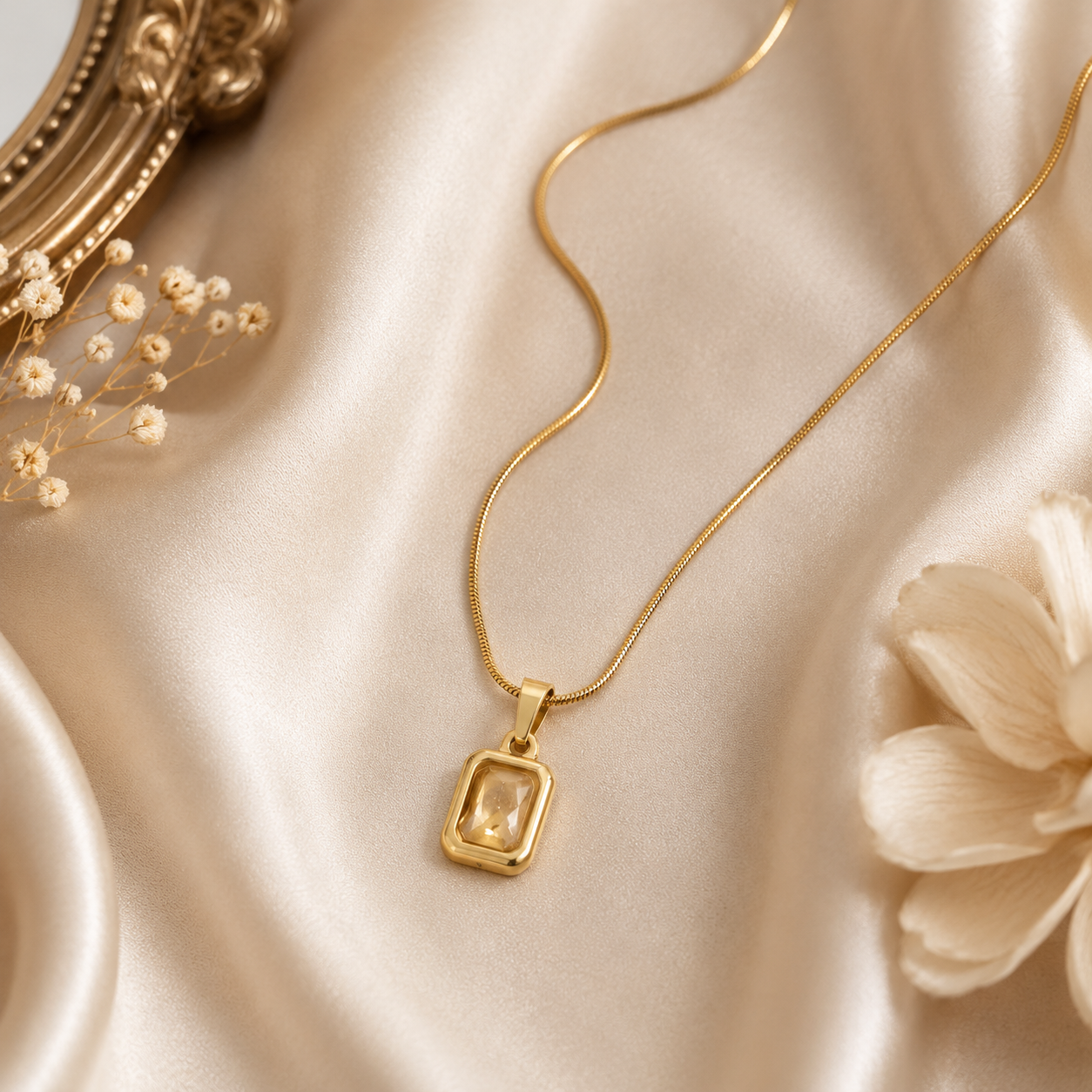Gold champagne CZ crystal rectangle pendant necklace on snake chain flatlay on marble with pink roses and baby's breath – romantic bridal jewelry anniversary gift