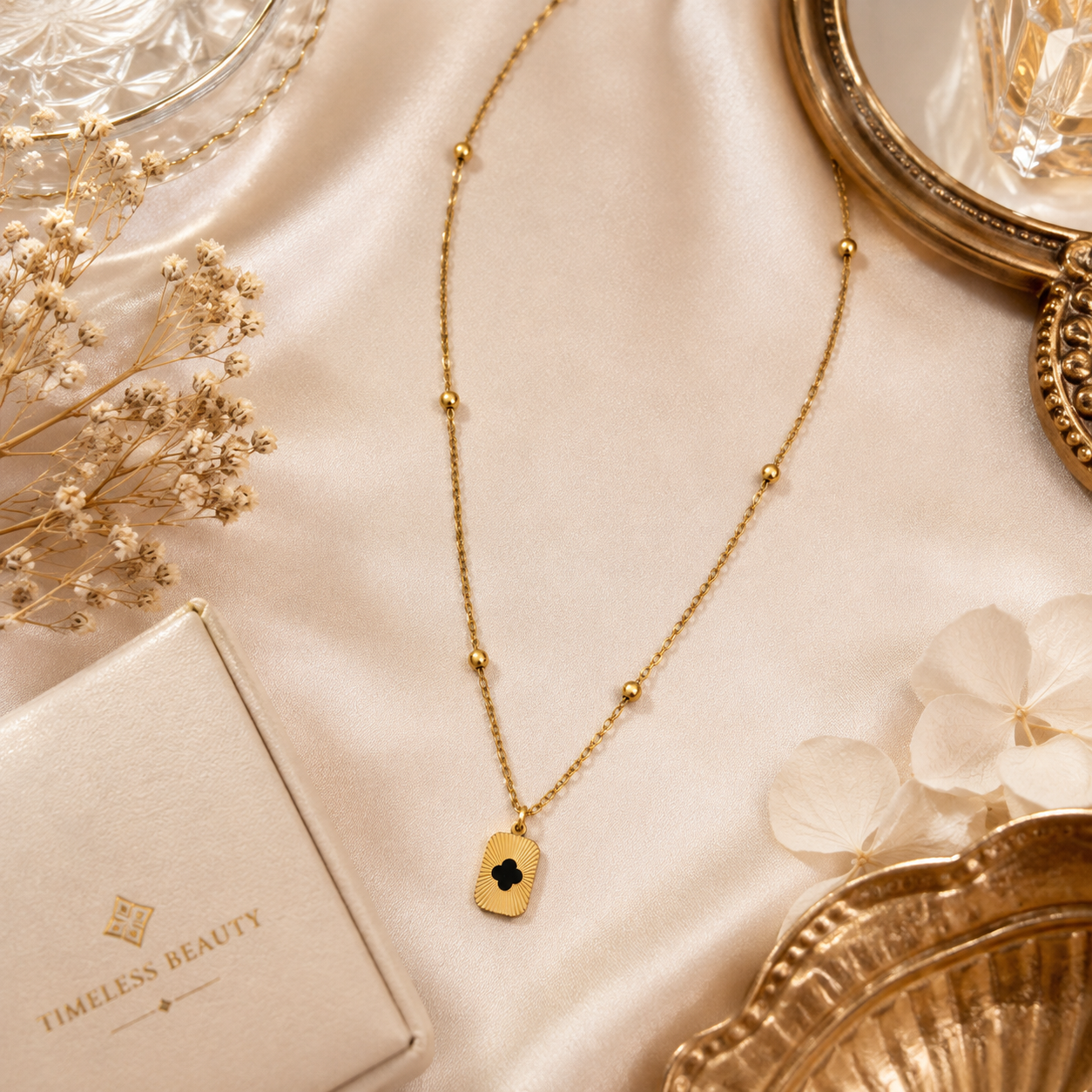 Gold sunburst clover tag pendant necklace on satellite chain flatlay on pink marble with pink roses and baby's breath – romantic bridal jewelry anniversary gift for her