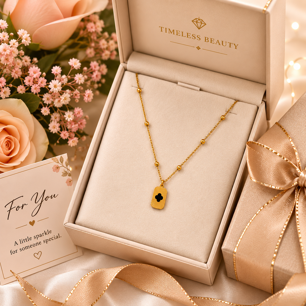 Gold clover cutout rectangle tag pendant necklace on satellite bead chain displayed on cream velvet jewelry bust in luxury jewellery boutique with 18K gold branding card – wedding guest necklace USA UK
