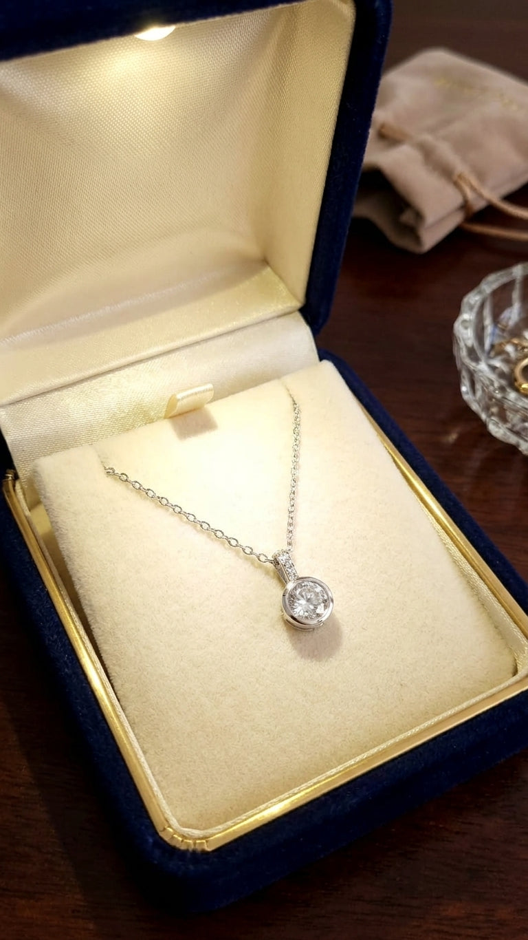 Silver round CZ solitaire pendant necklace on cable chain flatlay on blush pink satin with dried baby's breath, pearl bracelet and vintage silver ring box – bridal jewelry gift for her AureliaBlends