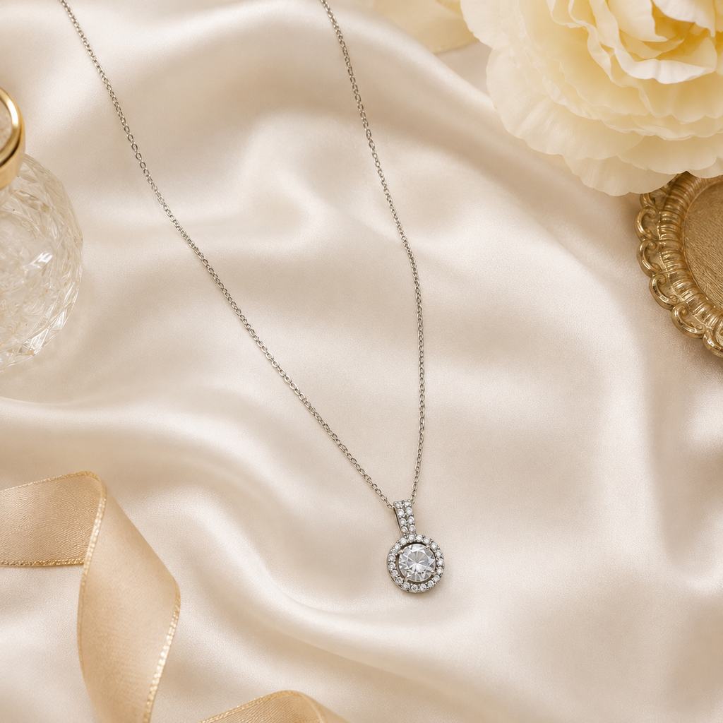 Silver CZ halo pendant necklace displayed on cream velvet jewelry bust in luxury jewellery boutique with 'Timeless Elegance' branding, gift boxes and white roses – formal occasion necklace UAE Australia