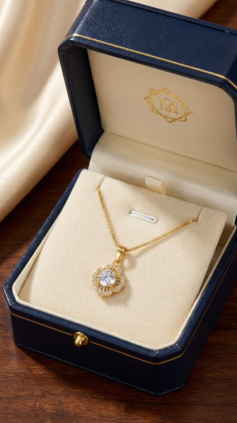 Gold floral sunburst CZ halo pendant necklace on box chain flatlay on cream satin with navy velvet gift box, cream roses, pearl stud earrings and jasmine flowers – bridal jewelry gift for her AureliaBlends