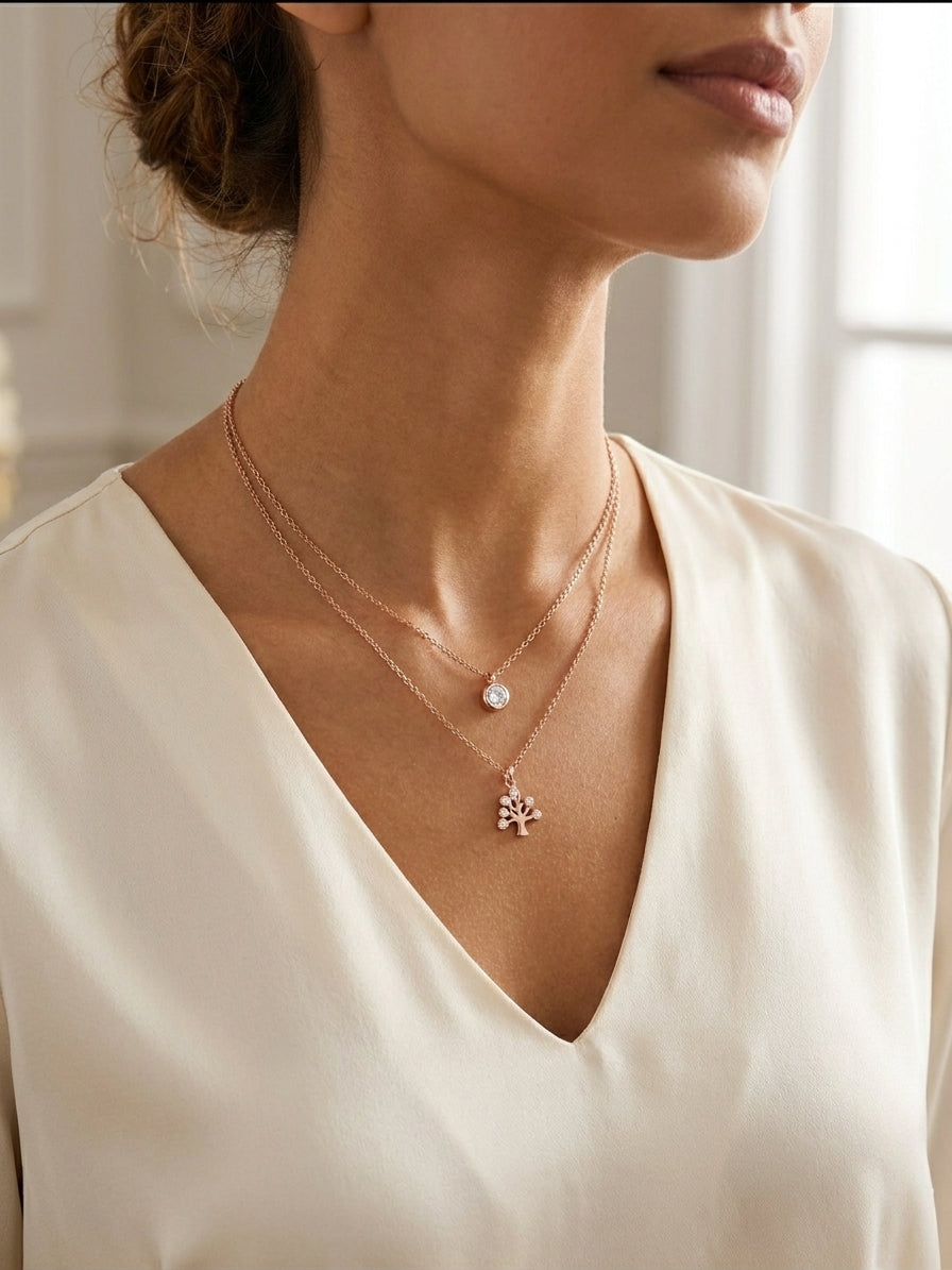 Rose gold double layer tree of life and CZ solitaire necklace flat lay on cream silk with dried leaves, gold mirror and rose petals – AureliaBlends