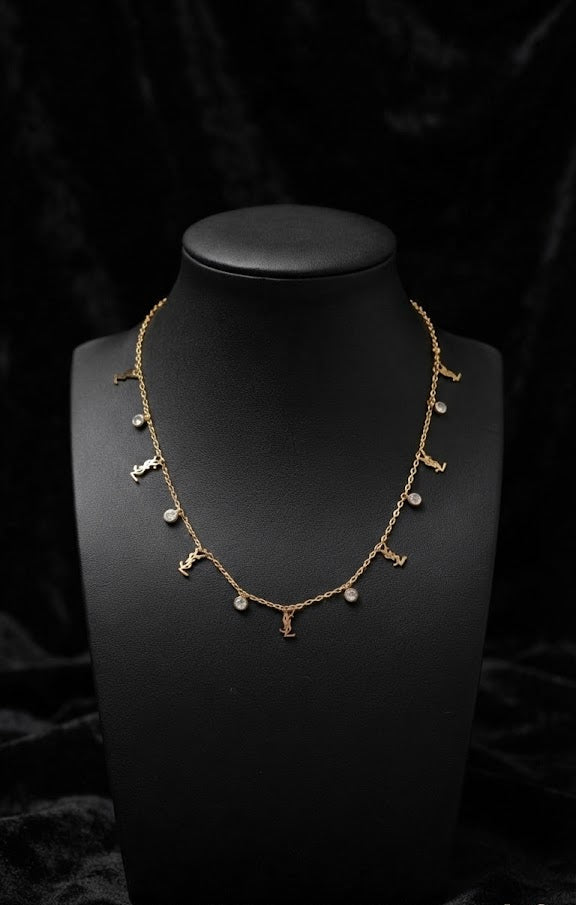 Dainty gold CZ station necklace on black marble bust surrounded by blush and burgundy roses in luxury jewellery boutique – AureliaBlends