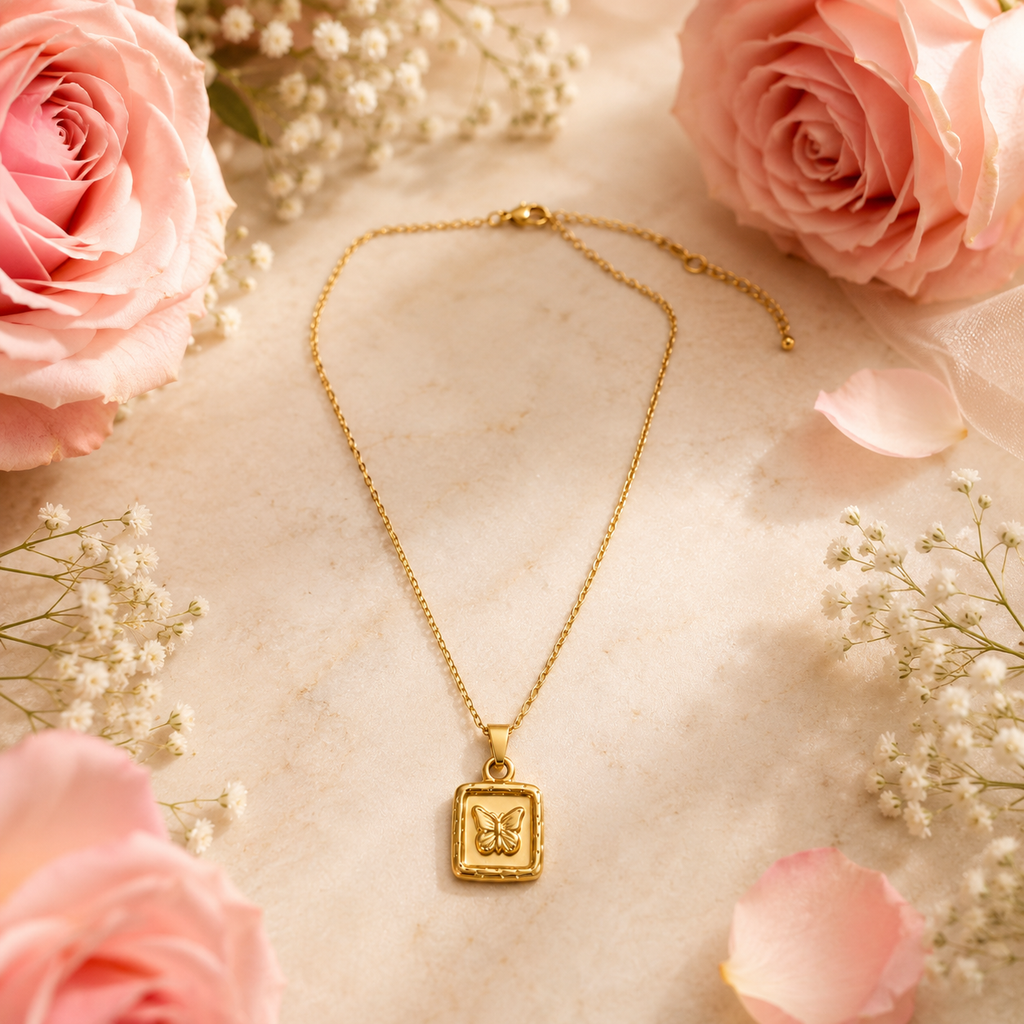 Gold butterfly square pendant necklace flat lay surrounded by pink roses and baby’s breath – dainty gold necklace gift AureliaBlends