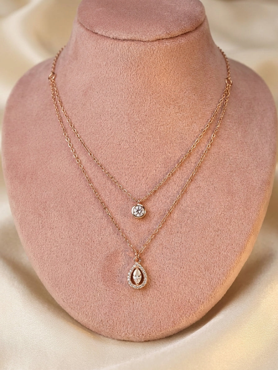 Indian woman wearing rose gold double layer CZ solitaire and teardrop pendant necklace in cream V-neck top smiling – AureliaBlends