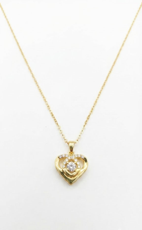 Woman wearing gold CZ swirl heart pendant necklace with cream turtleneck sweater in warm interior setting – AureliaBlends Forever Bloom Collection lifestyle shot