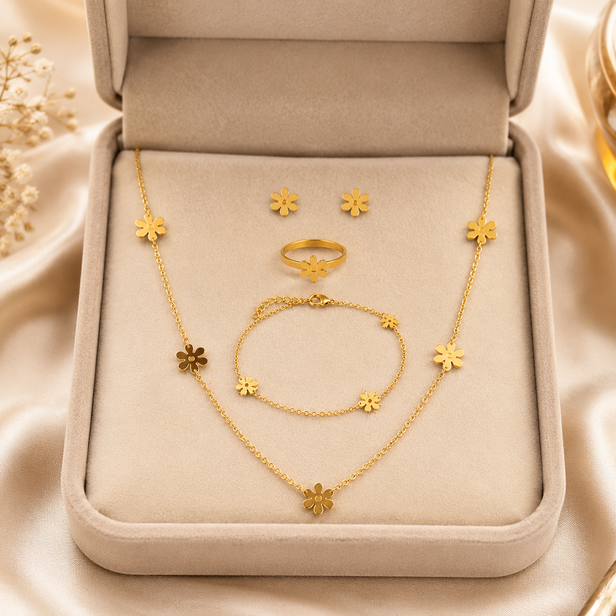 Gold daisy flower jewellery set flat lay on blush pink satin surrounded by peach and pink roses and baby’s breath – floral gold gift set for her AureliaBlends