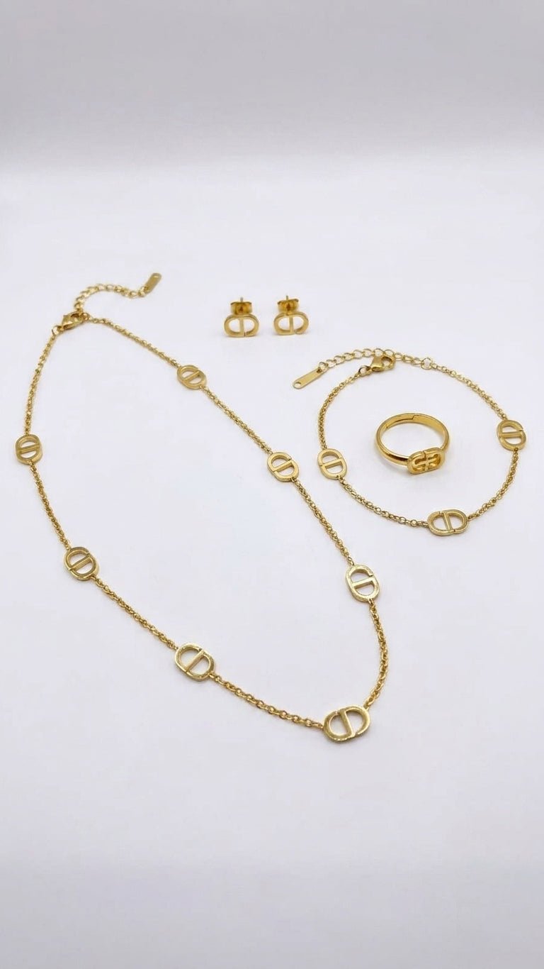 Gold mariner link 4-piece jewellery set flat lay on cream satin with ivory ribbon bow and glass jewellery dish – 18K gold-plated station necklace bracelet earrings ring set by AureliaBlends
