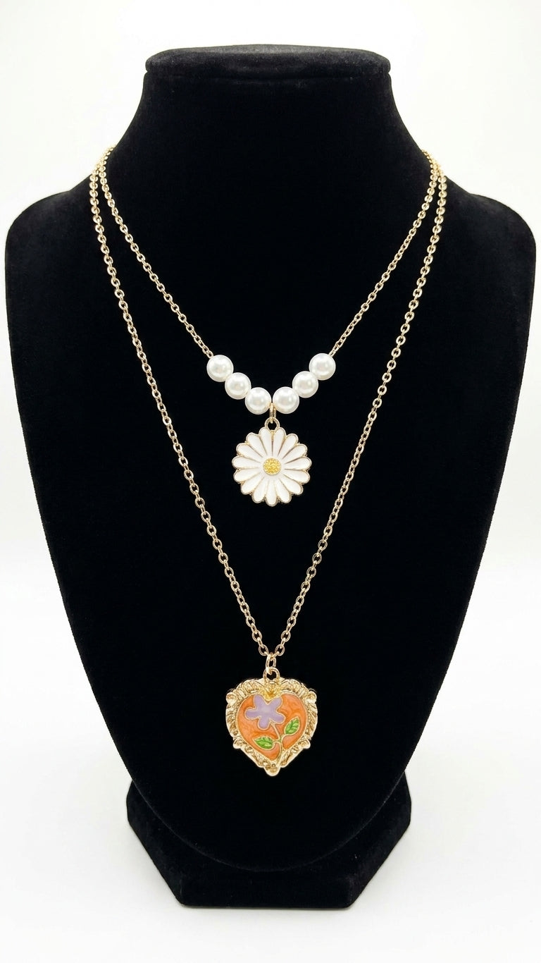 Gold double-layer pearl daisy pendant and orange enamel floral heart locket necklace set flat lay on cream satin with loose pearls and gold jewellery dish – romantic layered necklace gift by AureliaBlends