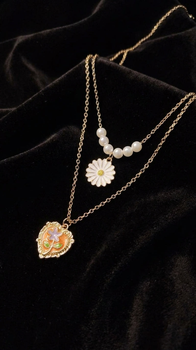 Gold layered pearl daisy and floral heart locket necklace set on black jewellery bust in luxury jewellery store display – premium double layer necklace by AureliaBlends