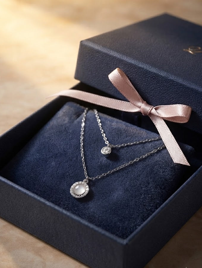 Silver double layer CZ solitaire and moonstone halo pendant necklace in open navy blue gift box with blush satin ribbon on warm wooden surface – AureliaBlends