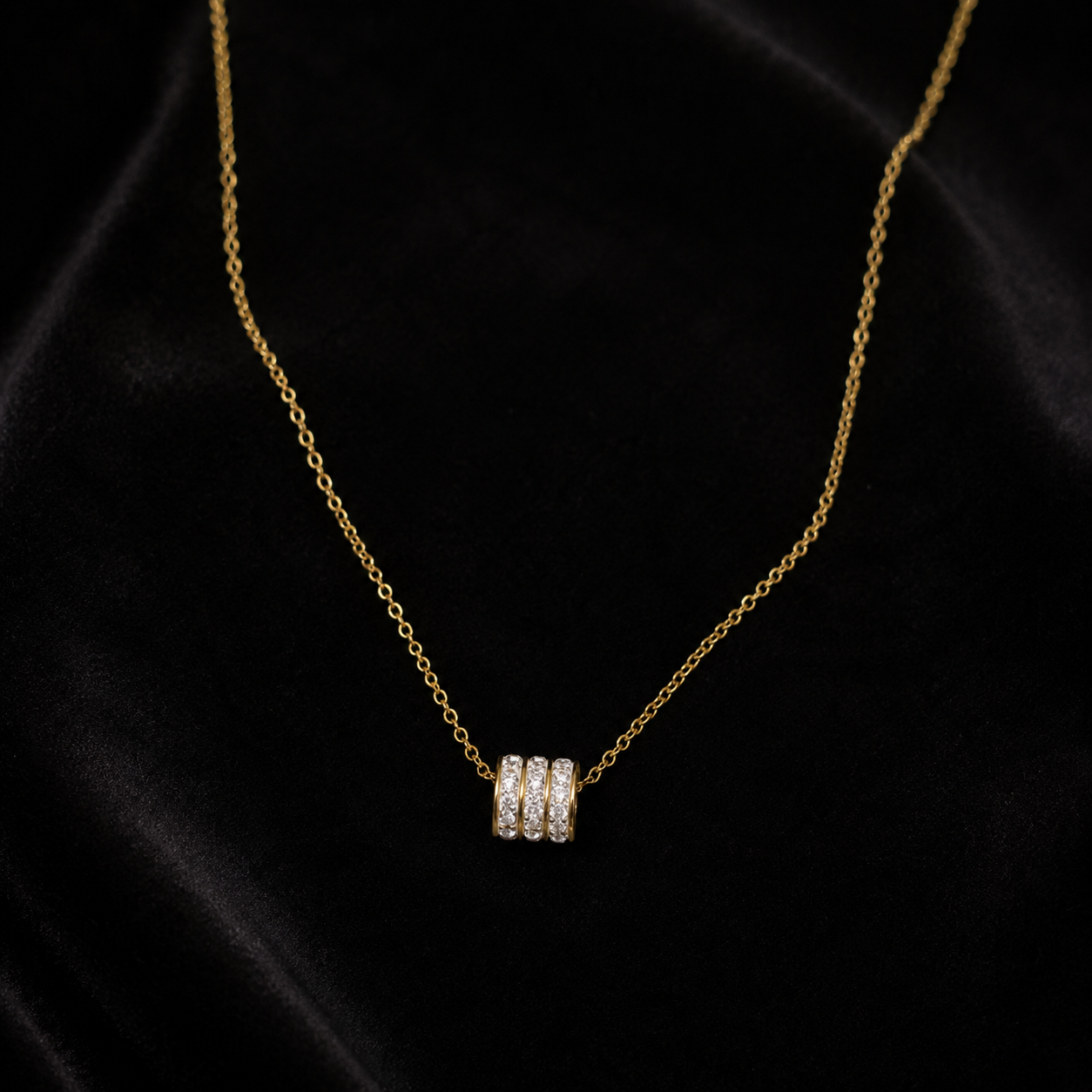 Gold triple pavé CZ crystal ring bead barrel pendant necklace on black jewellery bust in luxury gold jewellery store with warm lighting, cream flowers and gold display cases – premium diamond-look necklace AureliaBlends