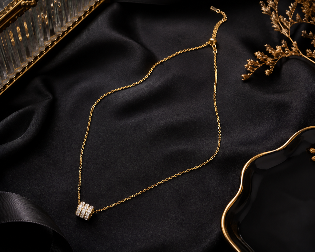 Gold triple pavé CZ crystal ring bead barrel pendant necklace on black jewellery bust in vibrant luxury jewellery boutique with colourful illuminated display cases, pink flowers and crystal candle holder – UAE luxury necklace AureliaBlends