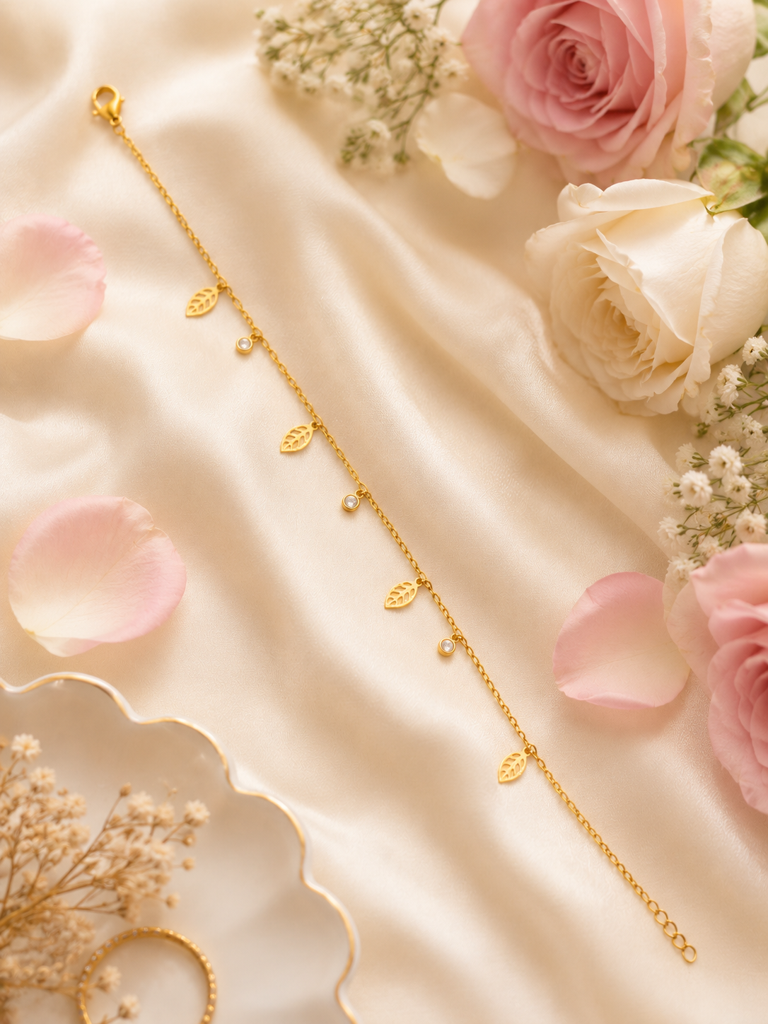 Gold leaf charm bracelet with CZ bezel dangles displayed on black velvet with dried flowers and gold decor – AureliaBlends