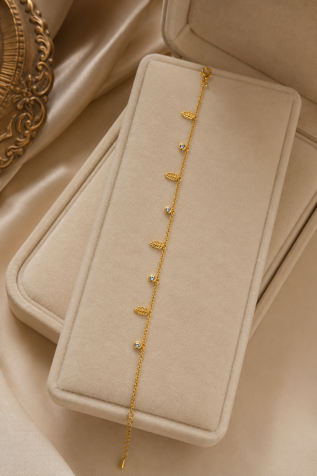 Dainty gold-plated leaf and CZ bezel dangle charm bracelet flat lay on cream silk with pink roses and gypsophila – AureliaBlends