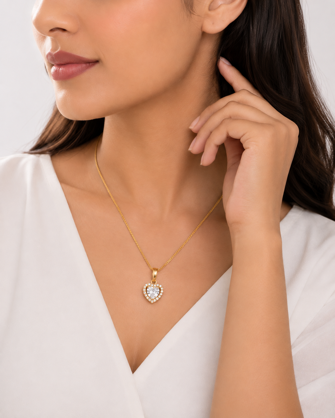 Gold heart halo CZ diamond solitaire pendant necklace flat lay on blush pink satin surrounded by pink garden roses and baby’s breath – Valentine’s Day heart necklace gift AureliaBlends