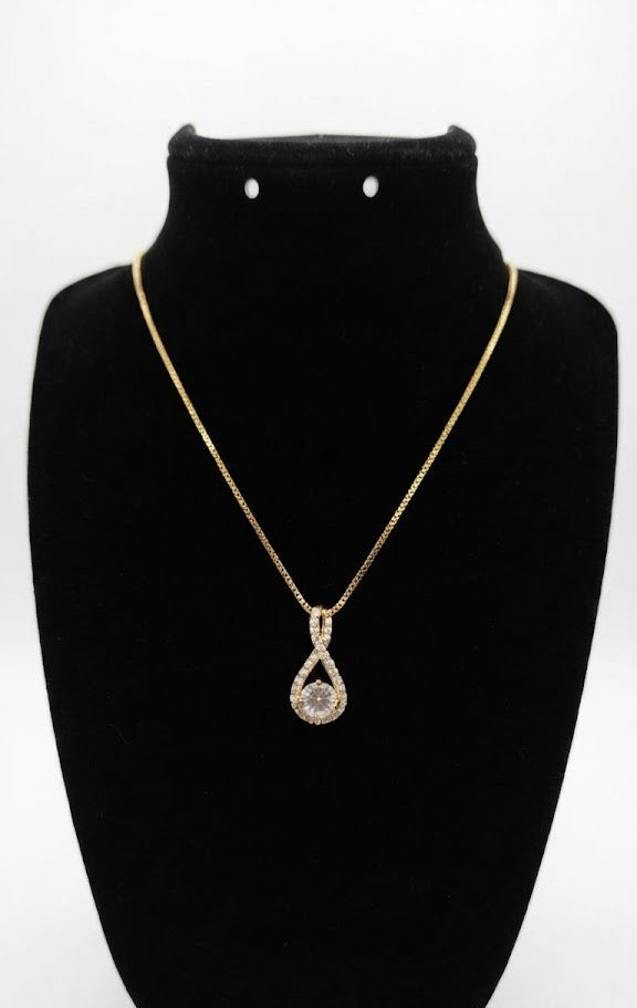 Gold CZ infinity teardrop pendant necklace worn by woman with dark silk top – close-up collarbone lifestyle shot