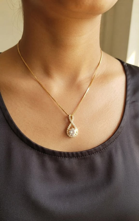 Gold CZ infinity teardrop pendant necklace on black jewelry bust against black background – full chain product shot