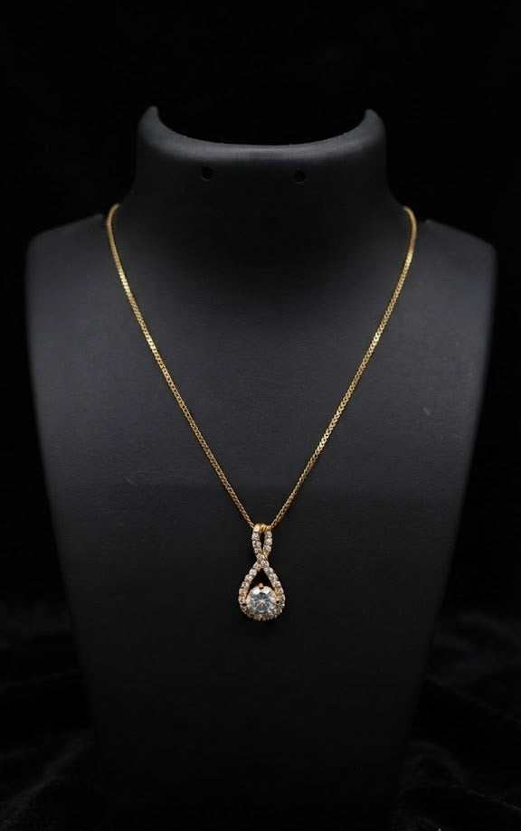 Gold CZ infinity teardrop pendant necklace styled on jewelry display with warm ambient boutique lighting – AureliaBlends
