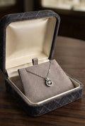 Silver CZ halo circle pendant necklace in open navy blue velvet gift box with For You tag on wooden surface with dried rose and silver stars