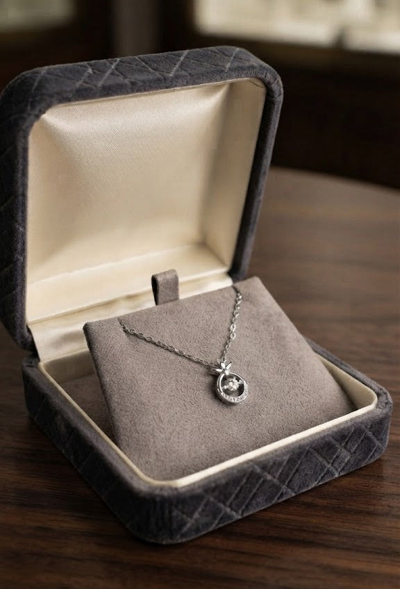 Silver CZ halo circle pendant necklace in open navy blue velvet gift box with For You tag on wooden surface with dried rose and silver stars