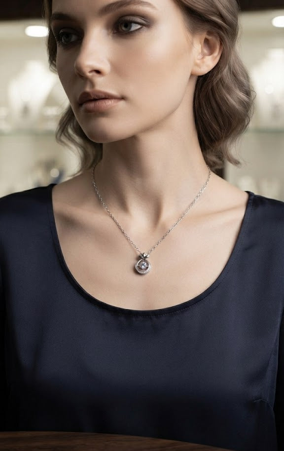 Silver crystal circle pendant necklace in navy blue velvet gift box with For You tag on dark marble surface with candle and dried rose
