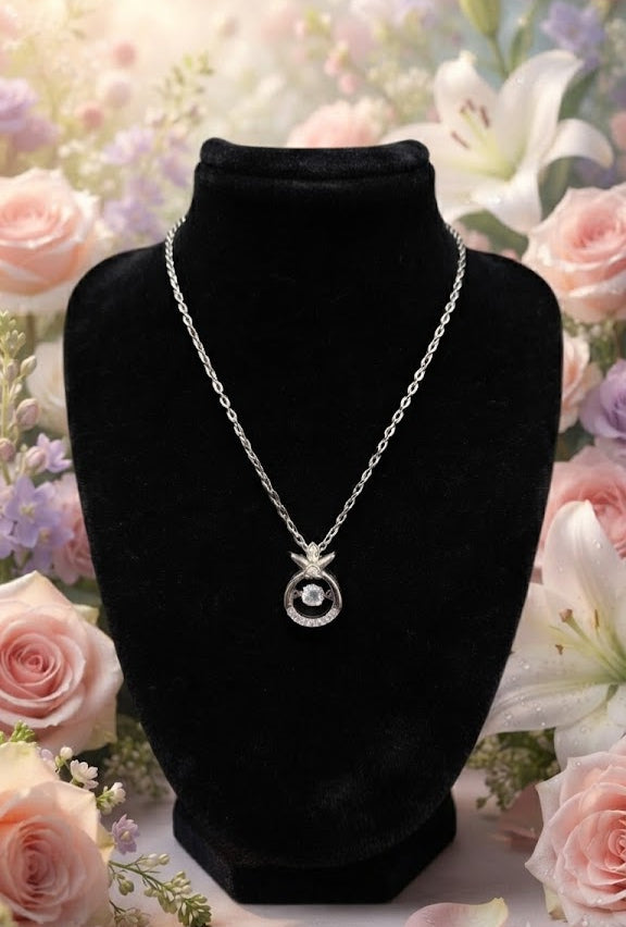 Silver CZ halo pendant necklace styled on jewelry display with warm ambient lighting – AureliaBlends