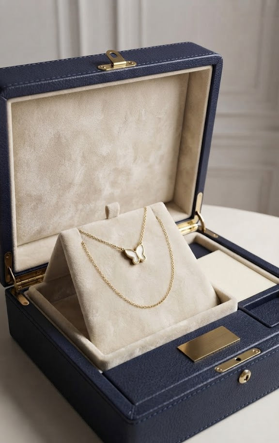 Gold butterfly mother of pearl shell pendant necklace in navy blue velvet gift box with ribbon and gift tags on wooden surface