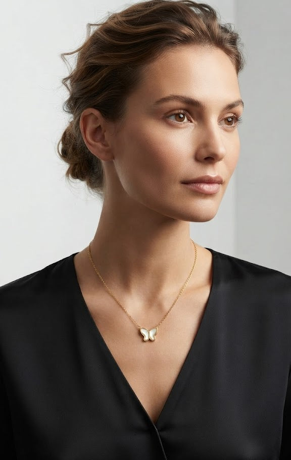 Gold butterfly mother of pearl necklace on black jewelry bust against black background – minimalist product shot