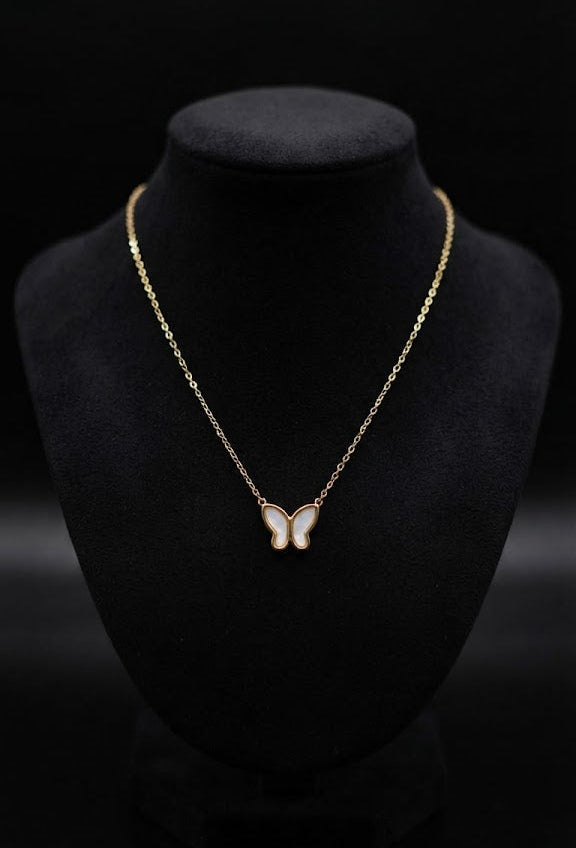 Gold butterfly mother of pearl necklace displayed on dark jewelry bust in luxury glass boutique case with Butterfly Collection nameplate