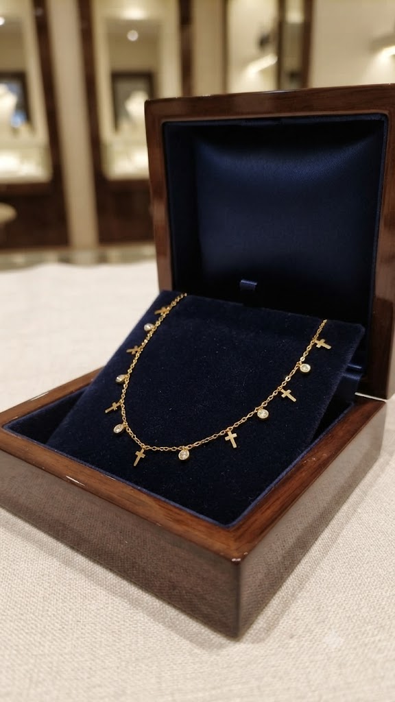 Gold cross charm and crystal necklace in open navy blue velvet wooden jewelry box in luxury boutique setting