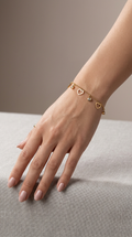 Woman wearing dainty gold-plated open heart and CZ bezel dangle charm bracelet on wrist resting on grey linen – AureliaBlends