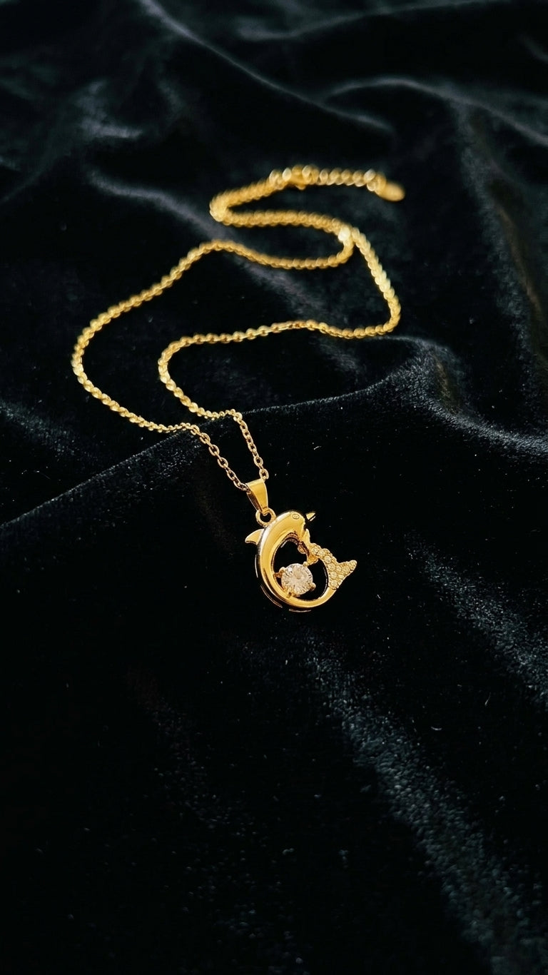 Gold dolphin CZ pendant necklace close-up on black velvet showing 18K gold-plated finish and cubic zirconia sparkle – AureliaBlends everyday necklace
