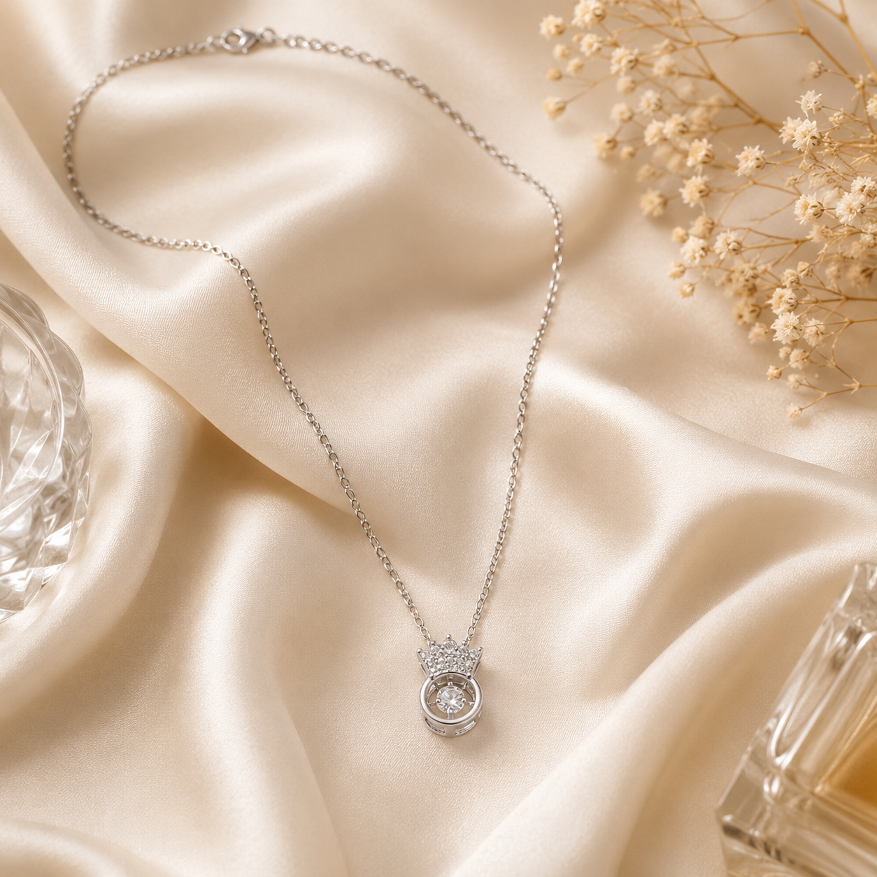 Silver CZ crown orbital pendant necklace on blush pink surface surrounded by pink roses, pink baby's breath and rose petals – AureliaBlends romantic bridal jewelry flat lay