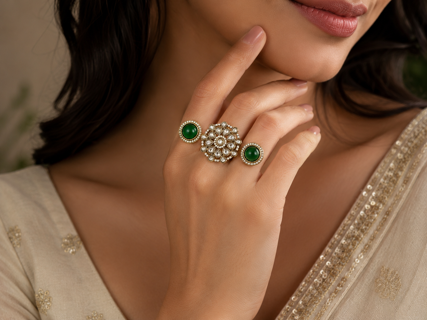 Indian woman wearing gold Kundan double finger ring with green cabochon side stones and polki crystal floral centrepiece on index and middle finger in cream embroidered saree – AureliaBlends