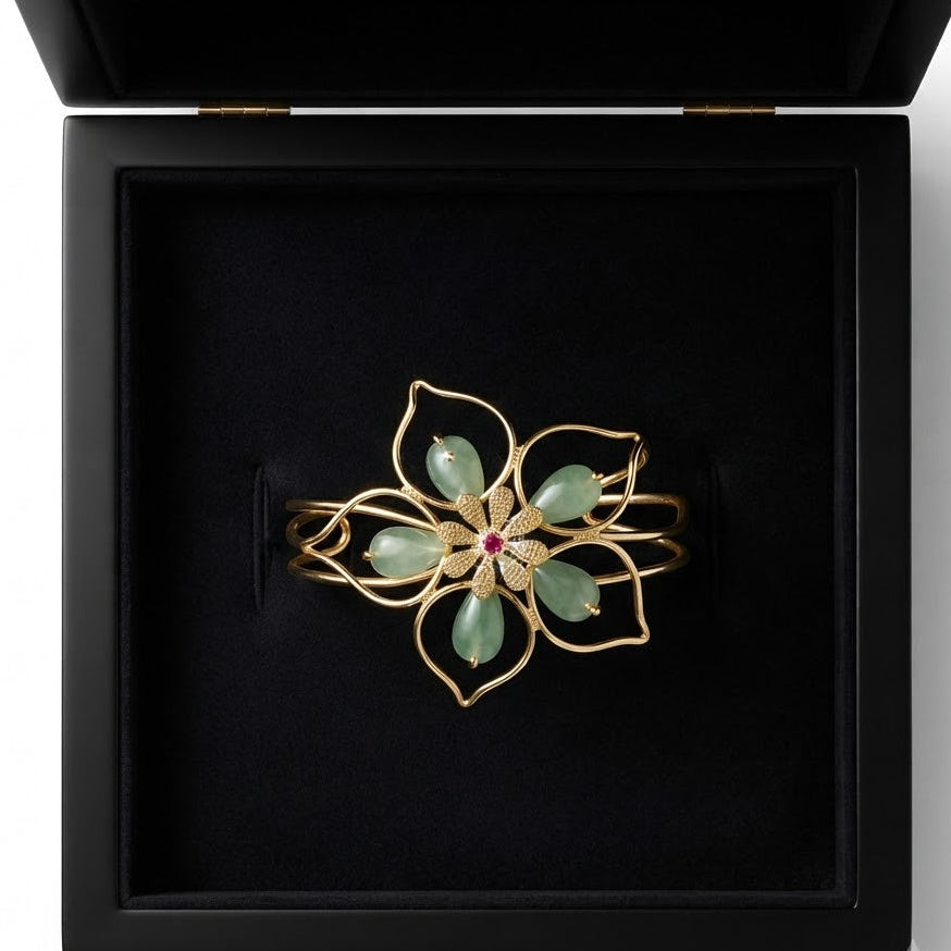 Gold open cuff flower bangle bracelet with green aventurine teardrop stones and ruby CZ centre displayed in open black velvet luxury jewelry box on white background – AureliaBlends