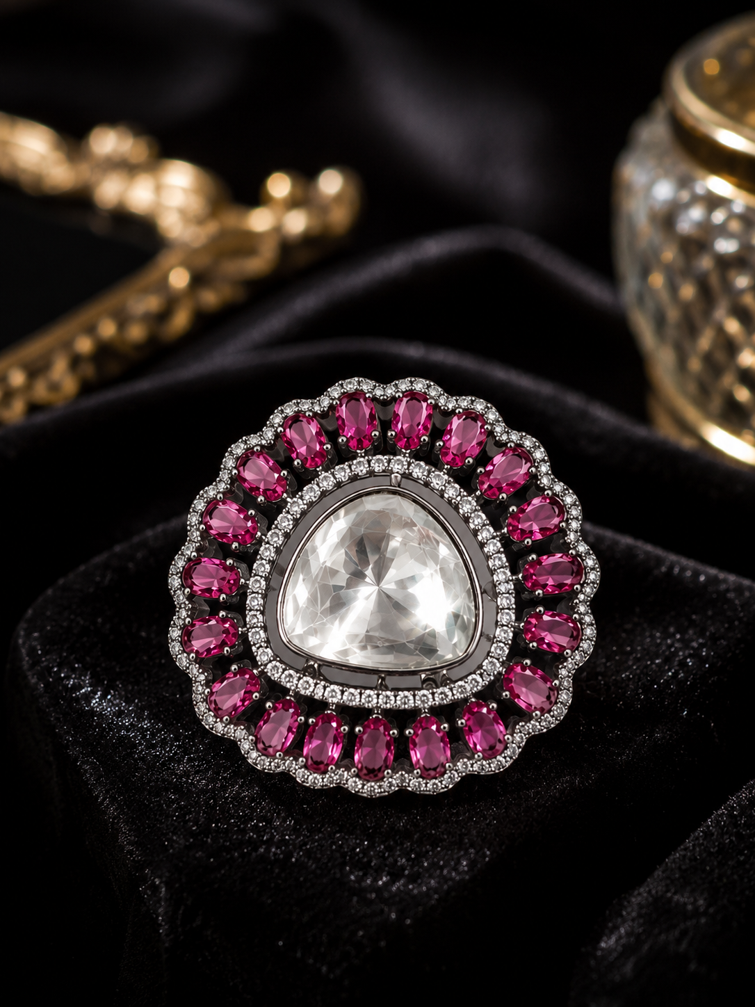 Silver polki cocktail ring with triangular uncut crystal and ruby red CZ double halo displayed on black velvet cushion in dark editorial setting with gold chain and glass decor in background – AureliaBlends