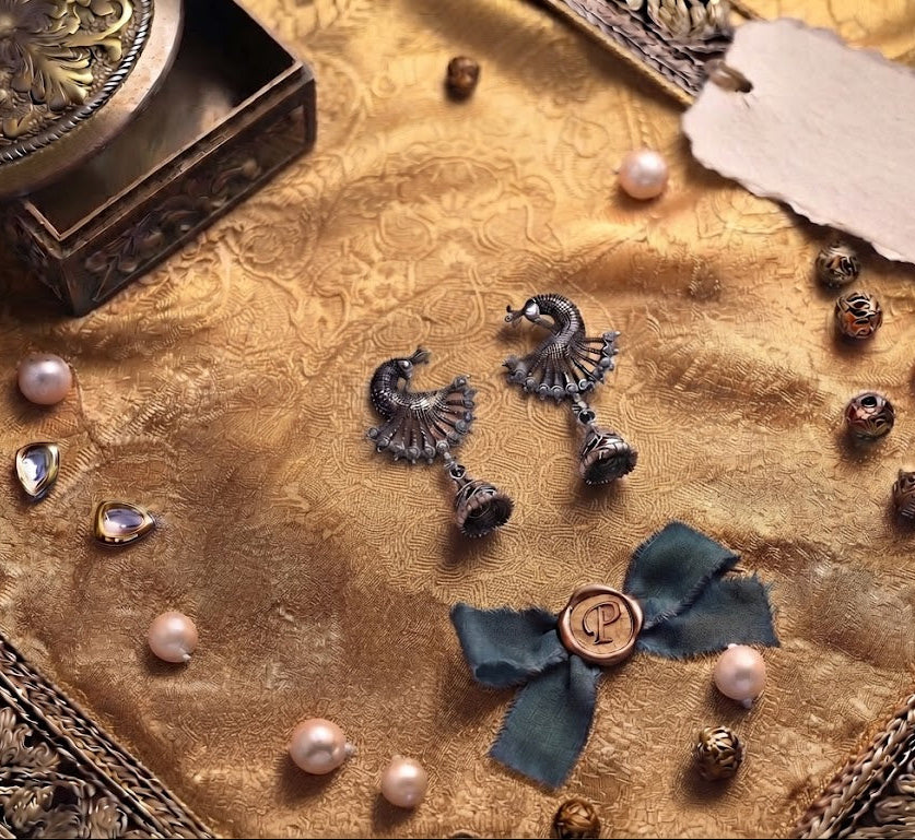 Close-up of oxidized silver peacock chandelier jhumka earrings in cream velvet box – bridal jewelry AureliaBlends