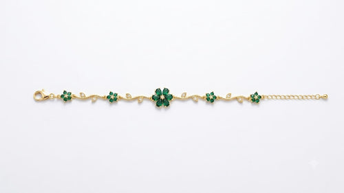 Woman wearing gold-plated emerald green CZ floral vine statement bracelet on wrist in white blazer – AureliaBlends