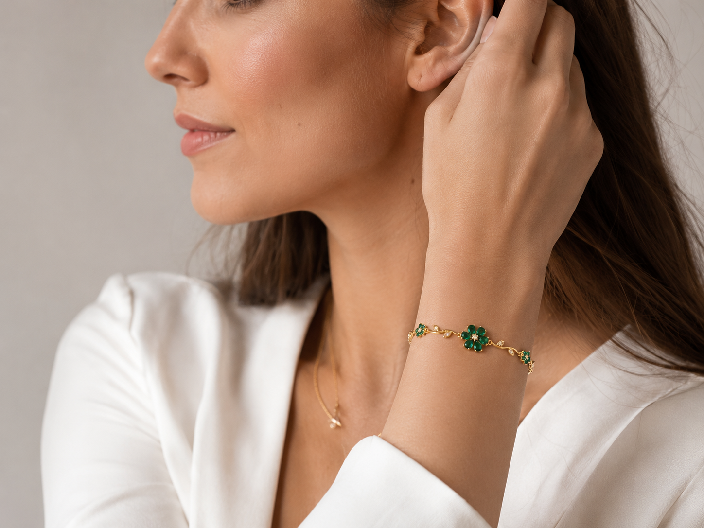 Gold-plated emerald green CZ floral vine bracelet flat lay on white background showing full design and lobster clasp – AureliaBlends
